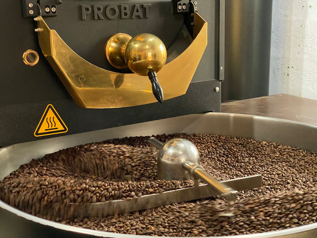 Close-up of coffee beans being roasted in a Probat industrial coffee roaster.